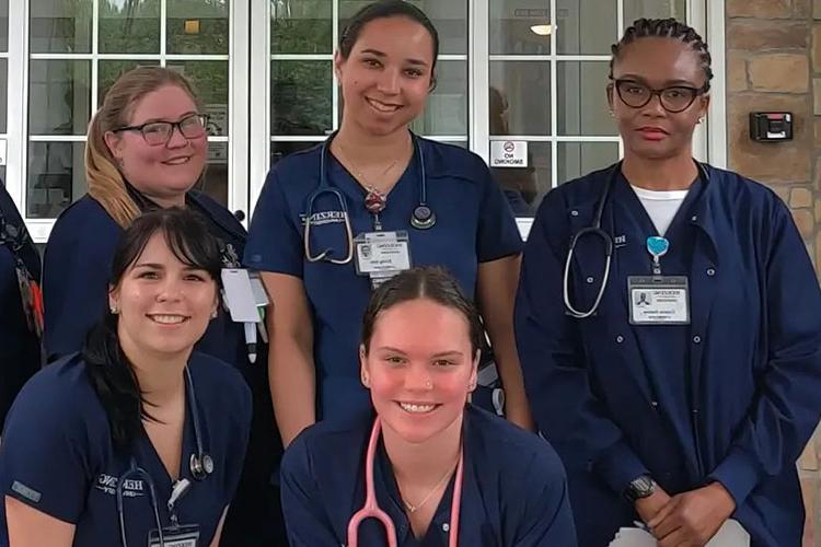 Herzing online associate in nursing students wearing blue scrubs smiling during intensive experience